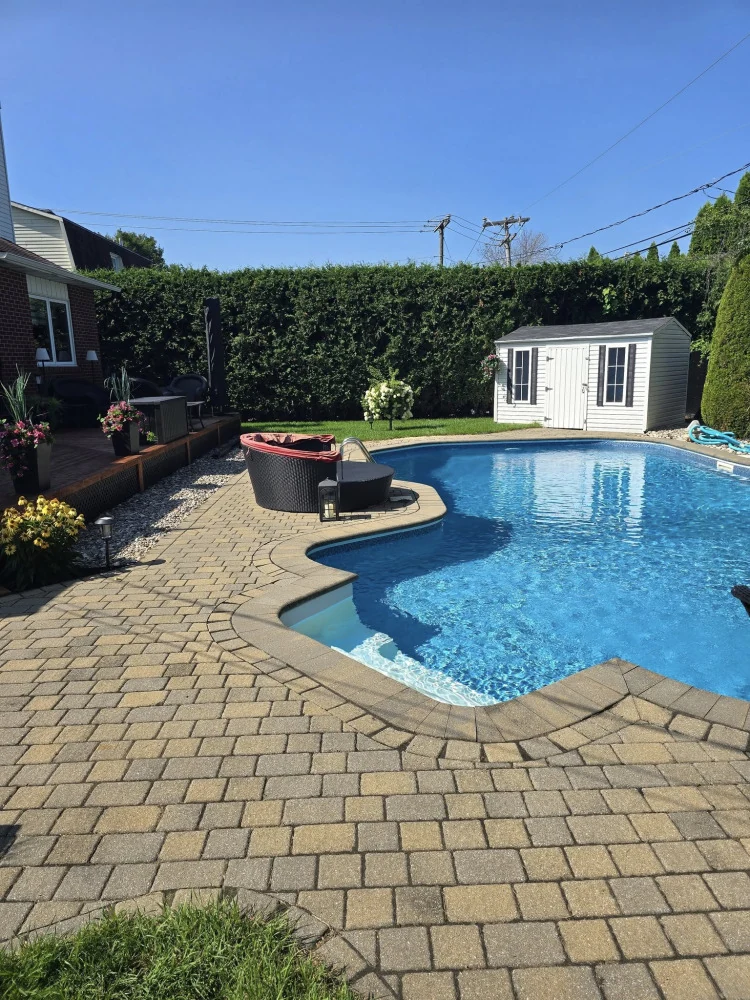 Terrasse en pavé uni aménagée autour d’une piscine résidentielle